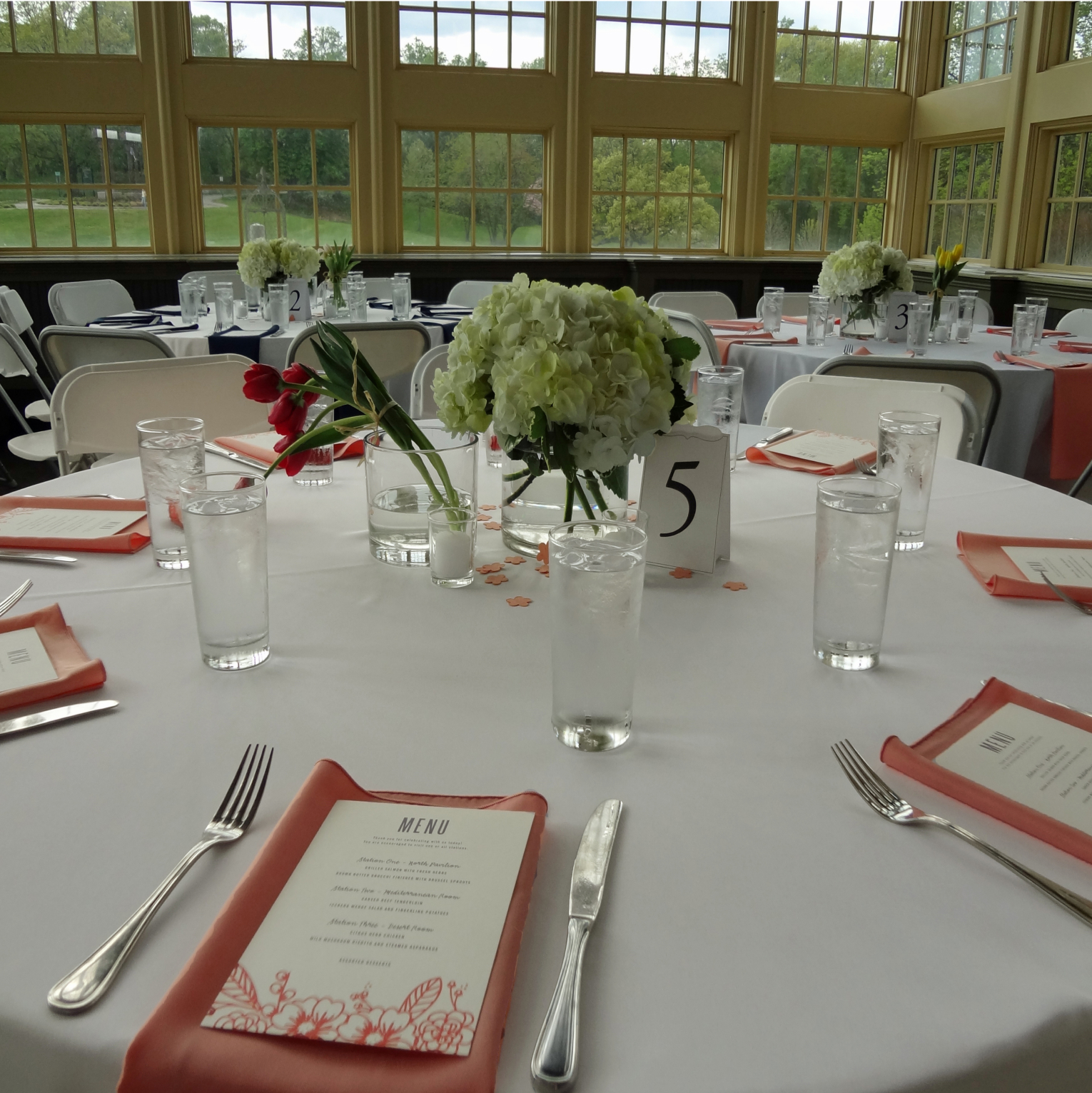The South Pavilion set for seated dinner with white linens on round tables and floral centerpieces